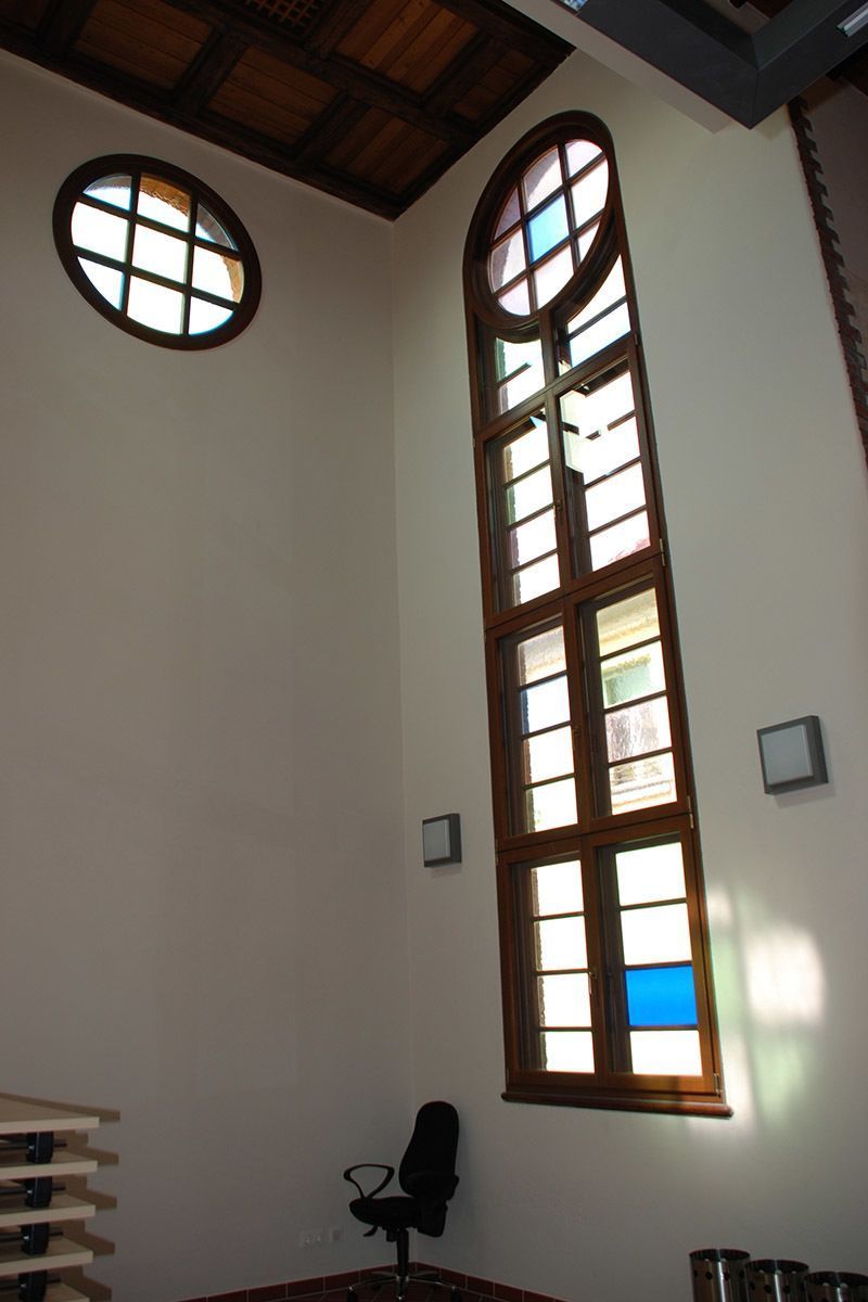 Ein Stuhl steht vor einem großen Fenster mit Buntglas