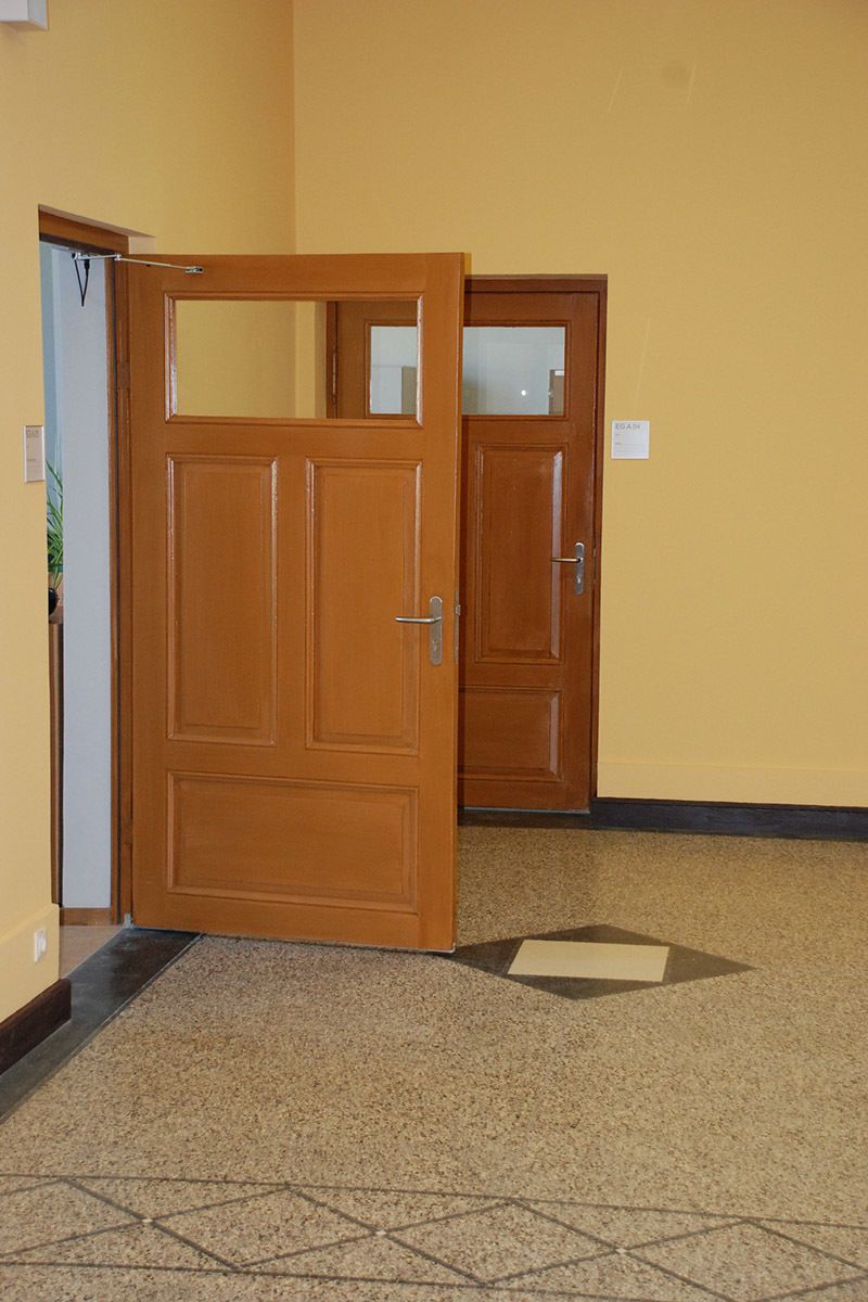 In einem Raum mit gelben Wänden steht eine Holztür offen