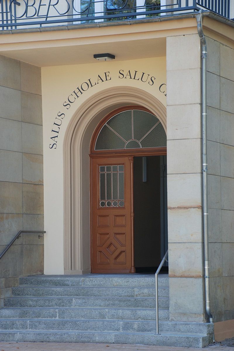 Der Eingang zu einem Gebäude mit einer Holztür und Treppe