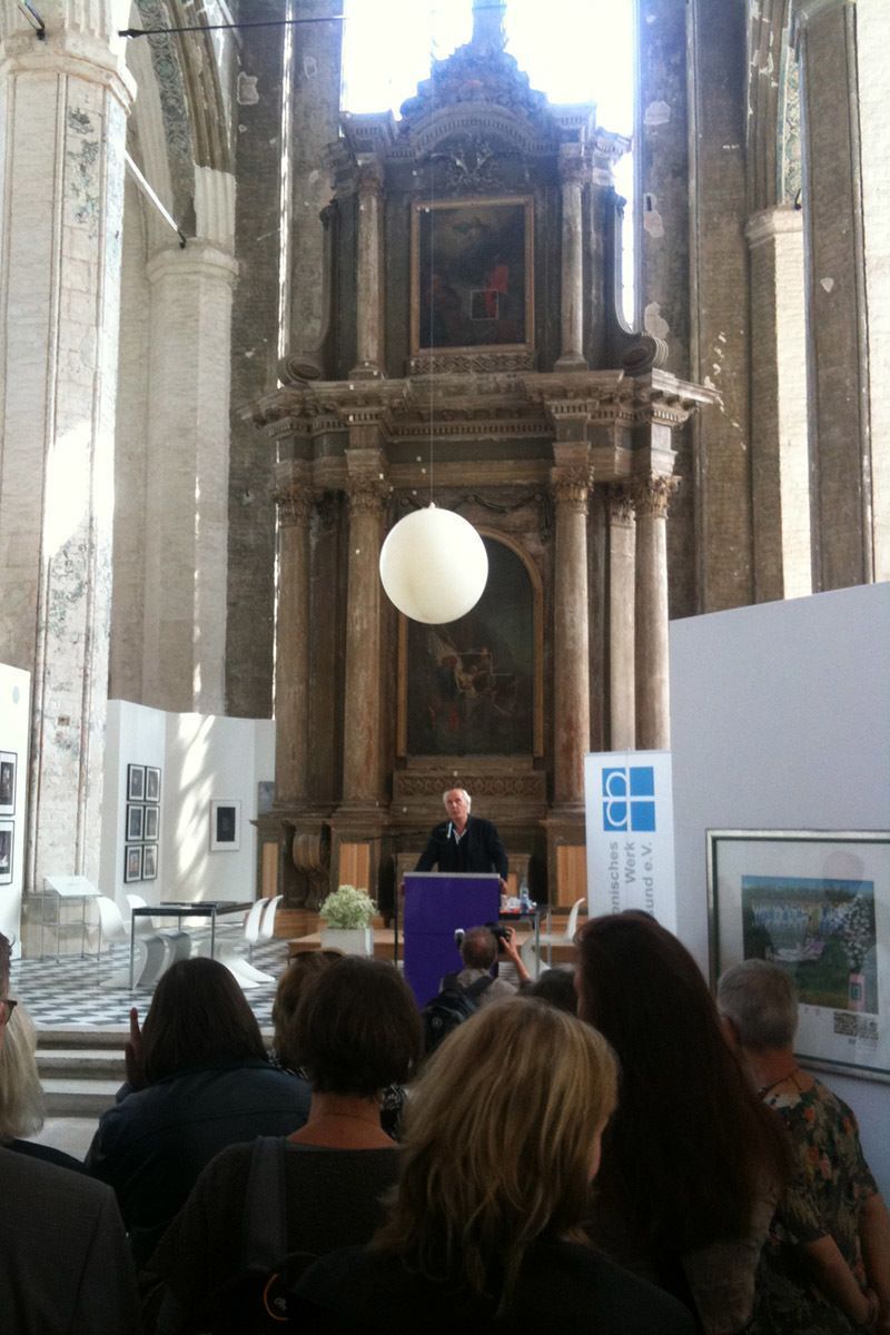 Ein Mann steht an einem Podium vor einer Menschenmenge in einer Kirche