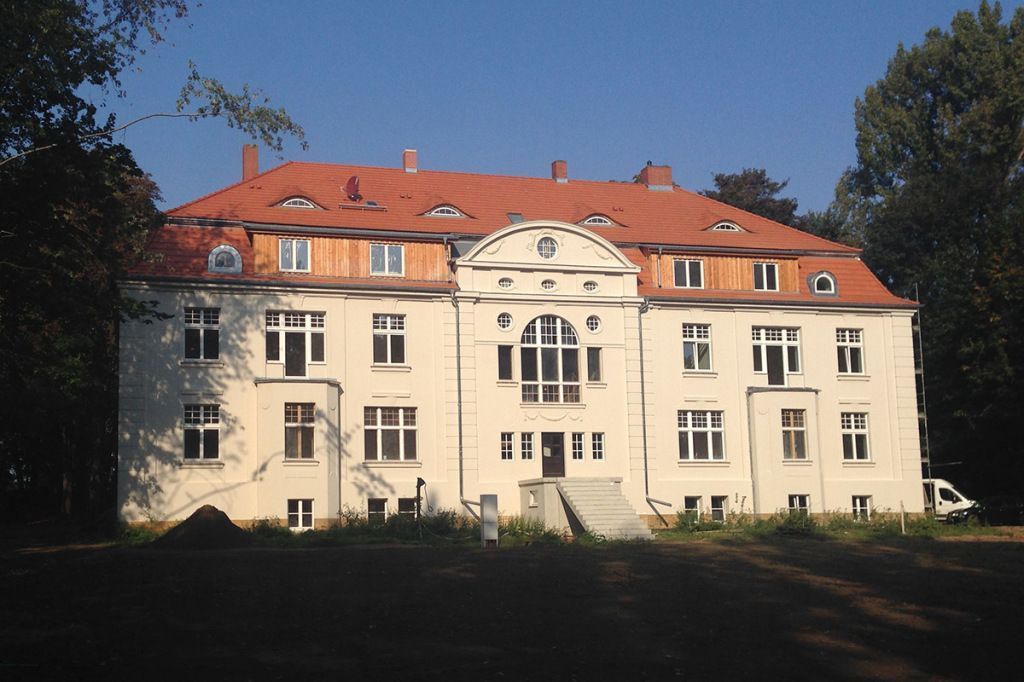 Ein großes weißes Gebäude mit einem roten Ziegeldach