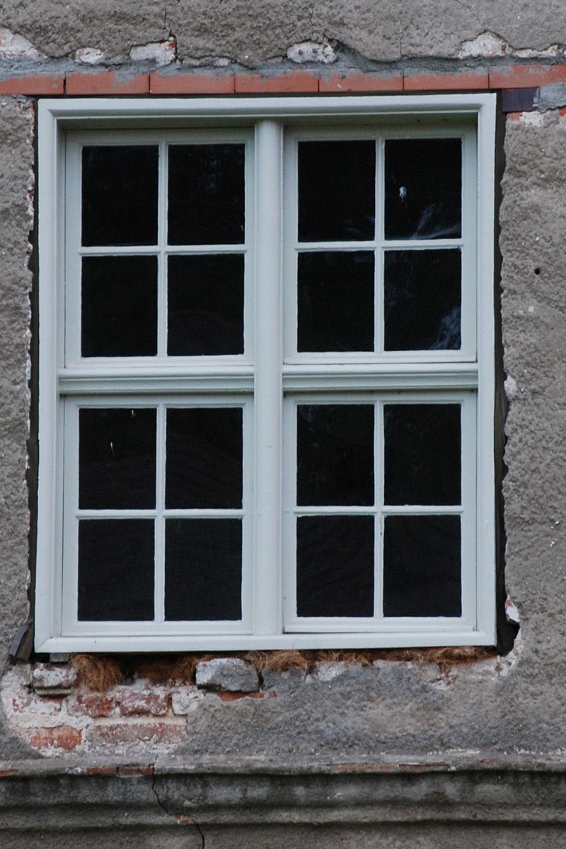 Ein Fenster mit weißem Rahmen und schwarzen Fenstern an einer Ziegelwand