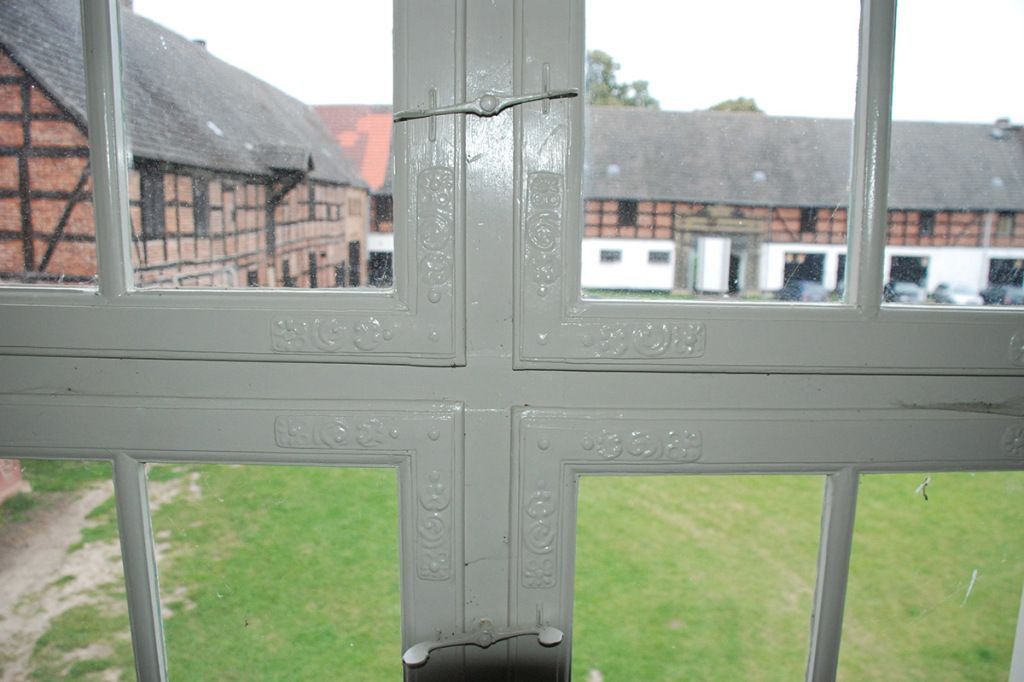 Ein Fenster mit Blick auf ein Feld und ein Gebäude im Hintergrund.