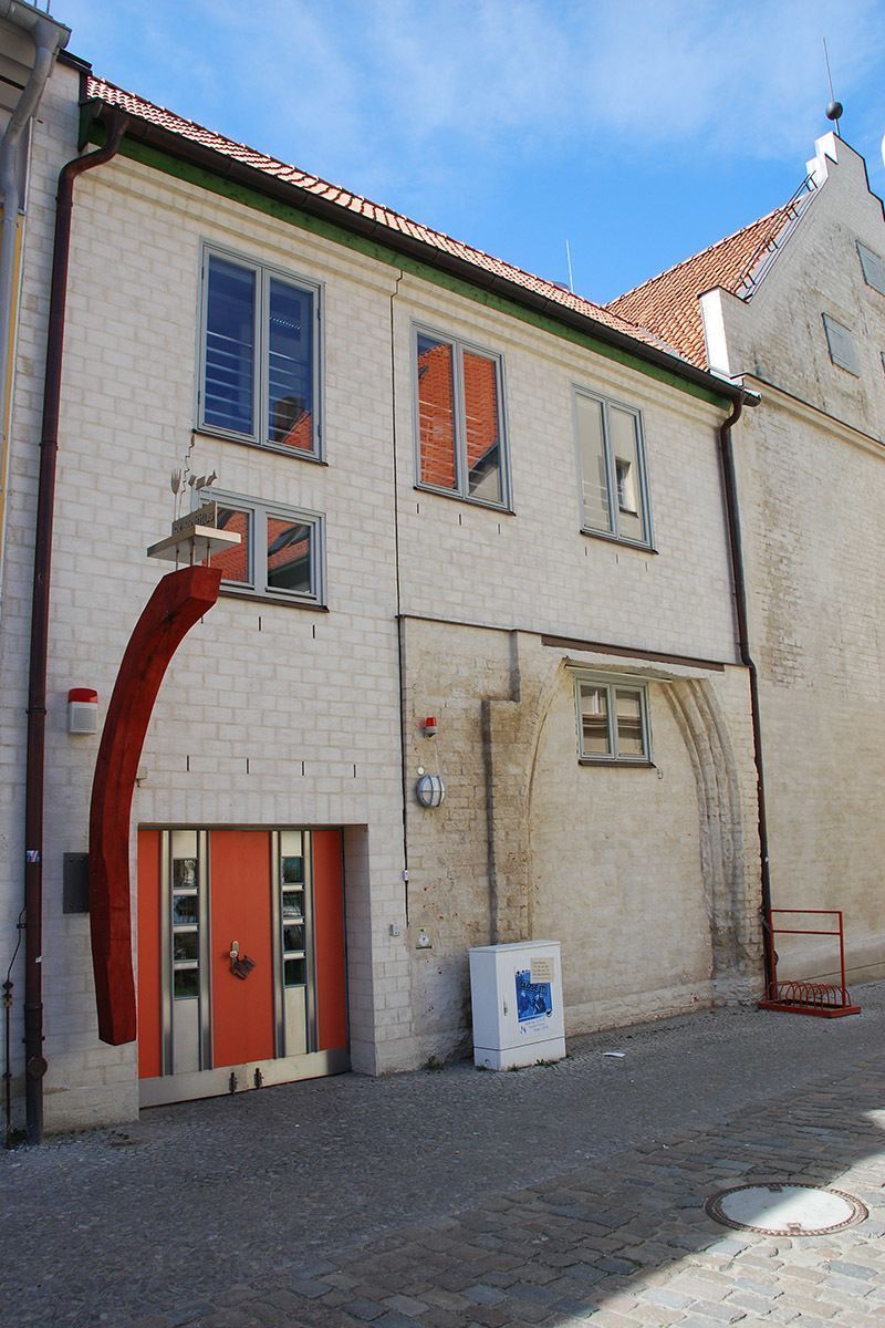 Ein weißes Gebäude mit einer roten Tür und einem grünen Dach