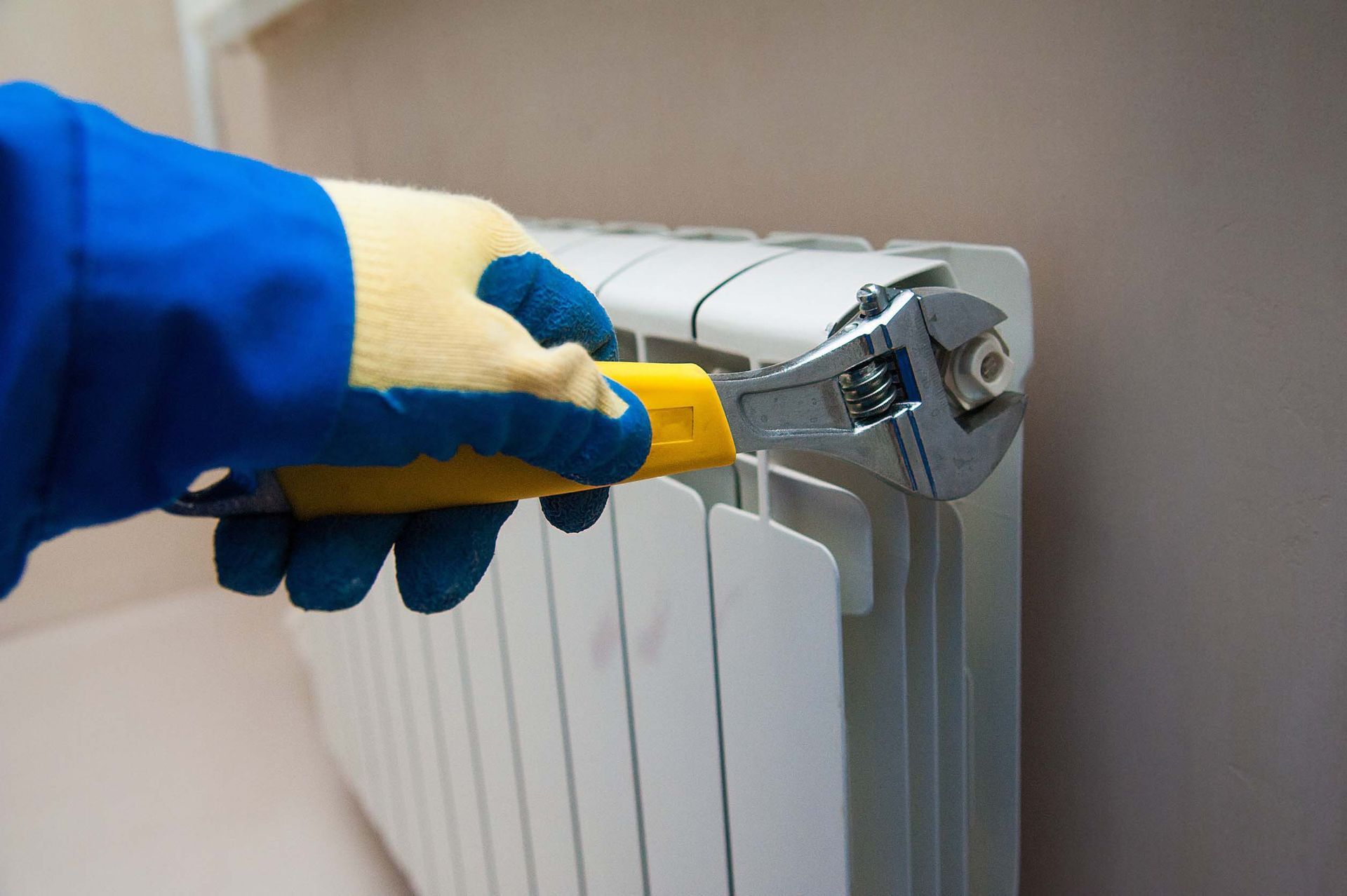 Una persona está arreglando un radiador con una llave inglesa.