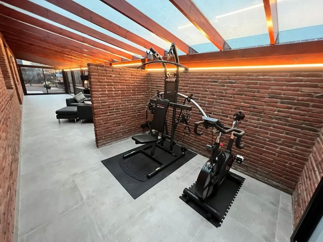 Un gimnasio con una bicicleta y una cinta de correr en una habitación con una pared de ladrillos.