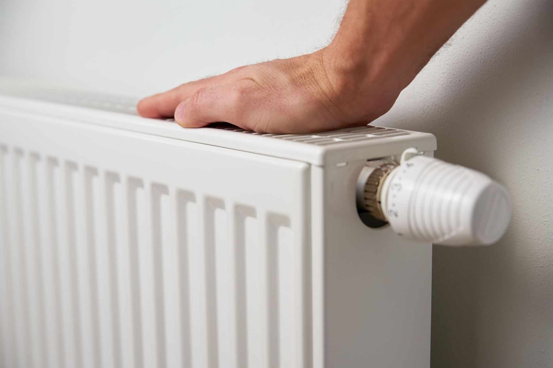 Una persona está tocando un radiador con la mano.