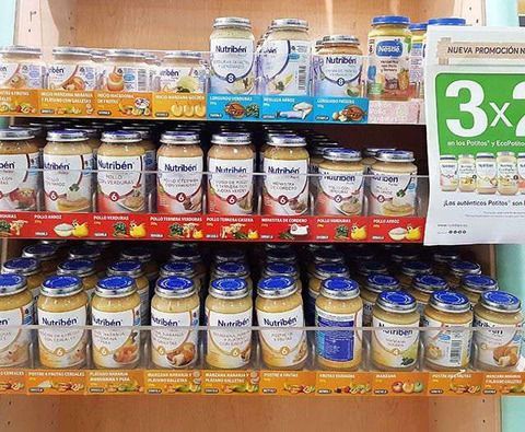 Un estante lleno de frascos de comida para bebés y un cartel que dice 3x2