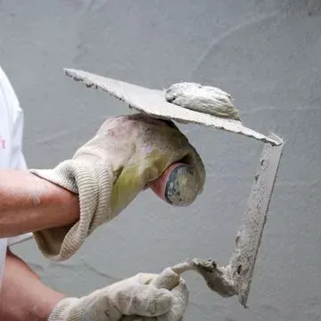 Pratissoli & Co. Umbauten - Person mit Arbeitshandschuh hält einen Spachtel mit Rigips