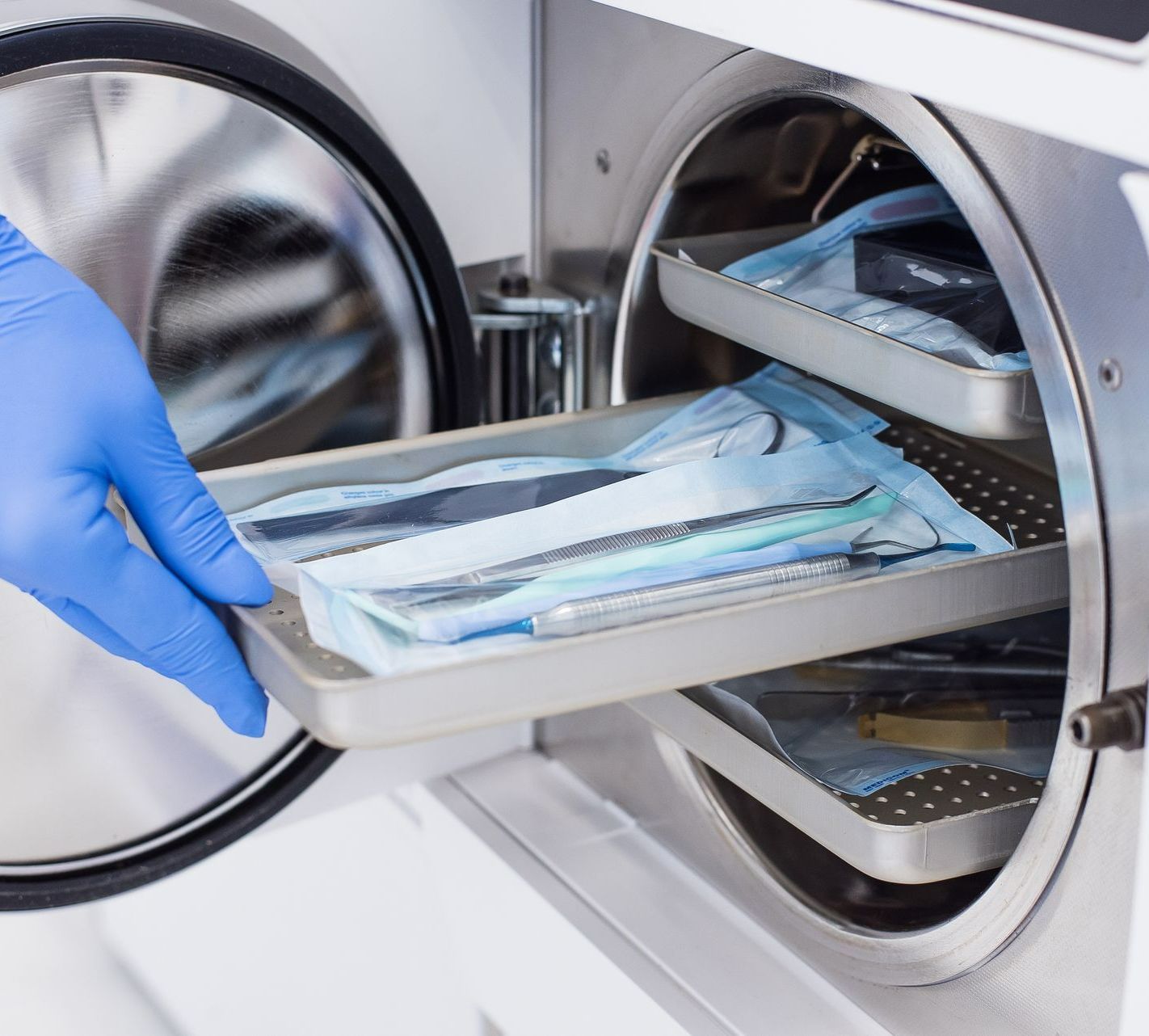 Personne sortant un plateau d'un autoclave