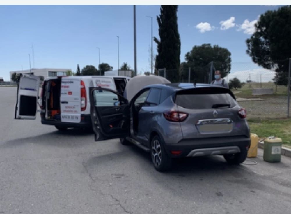 Un coche está aparcado al lado de una furgoneta con las puertas abiertas.