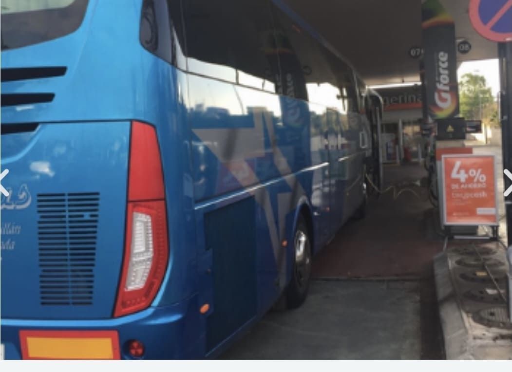 Un autobús azul está estacionado frente a un cartel que dice glace
