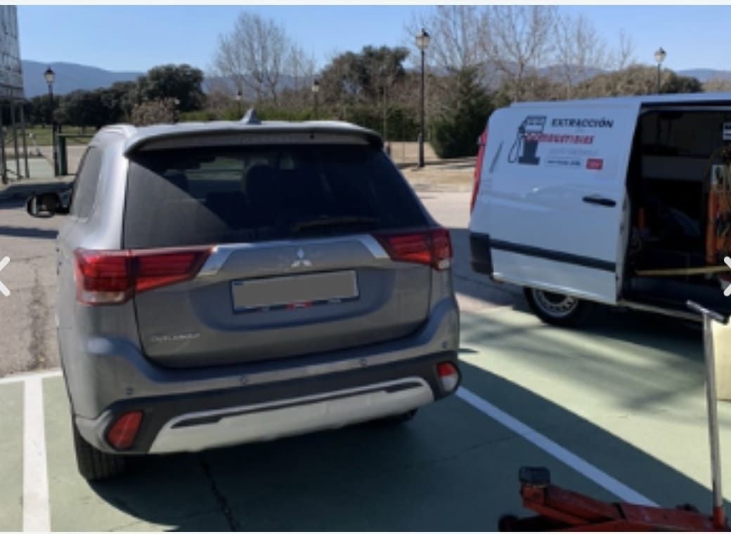 Un Mitsubishi Outlander está estacionado al lado de una camioneta blanca.