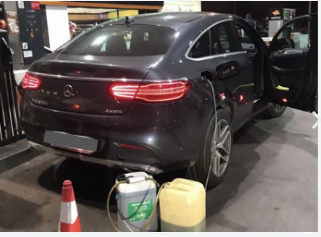 Un coche se está llenando de gasolina en una gasolinera.