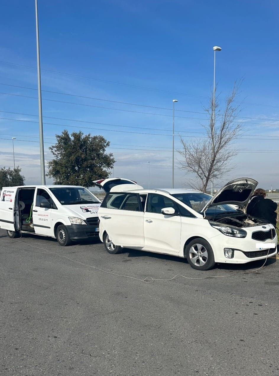 Dos coches blancos están aparcados en un aparcamiento con el capó abierto.