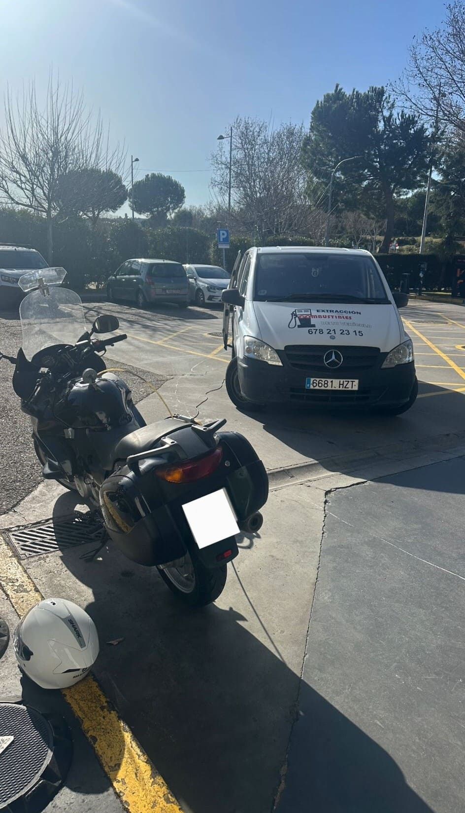Dos motocicletas están estacionadas al lado de una camioneta blanca en un estacionamiento.