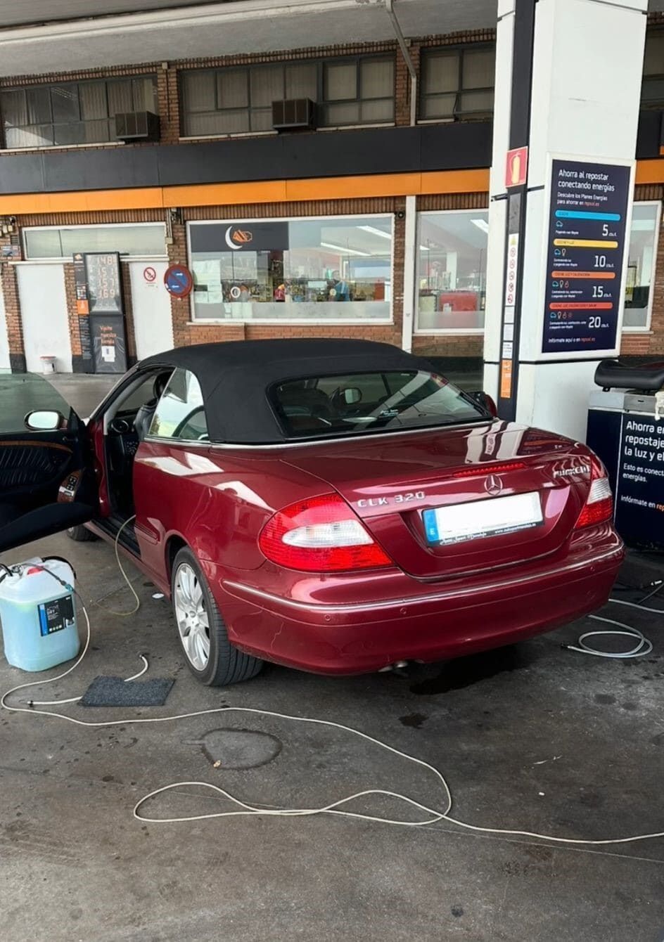 Un coche rojo descapotable está aparcado en una gasolinera.