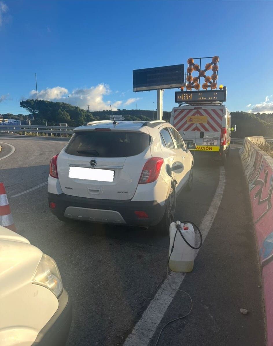 Un coche blanco está aparcado al costado de la carretera.