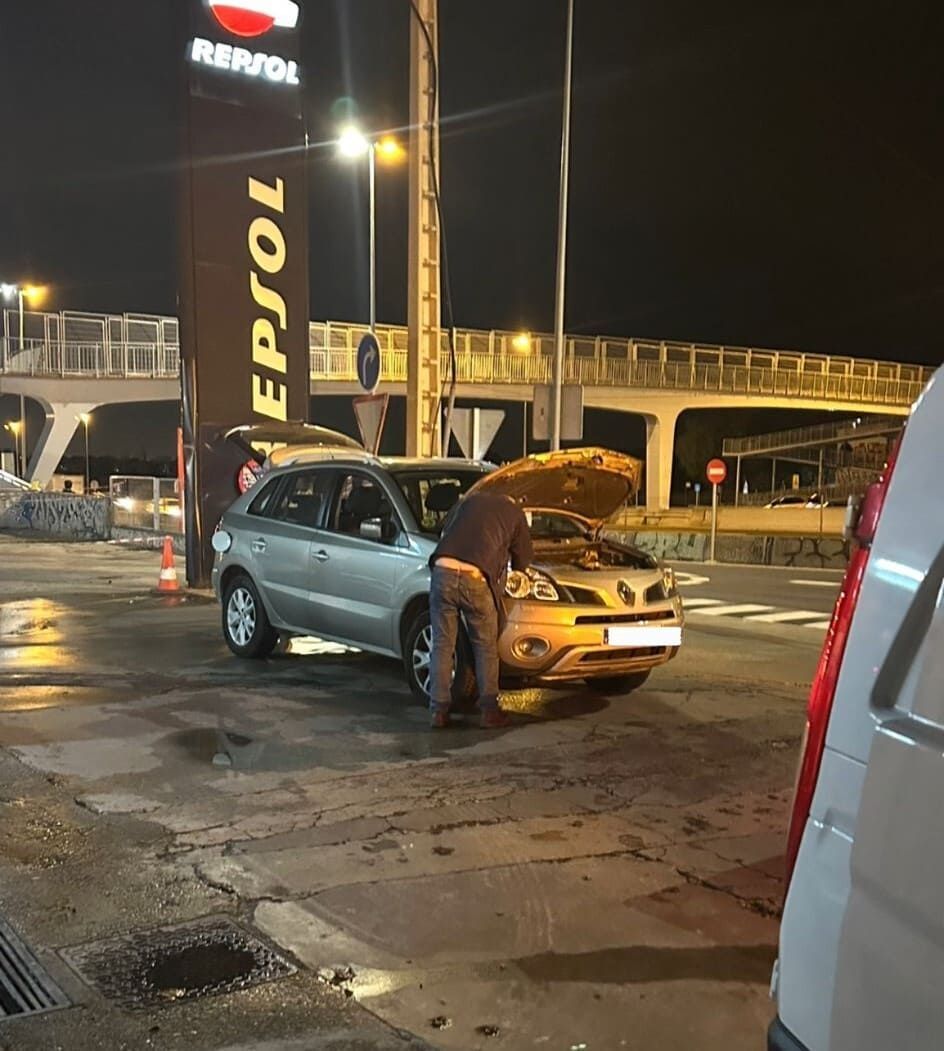 Un hombre está trabajando en un coche en una gasolinera Repsol.