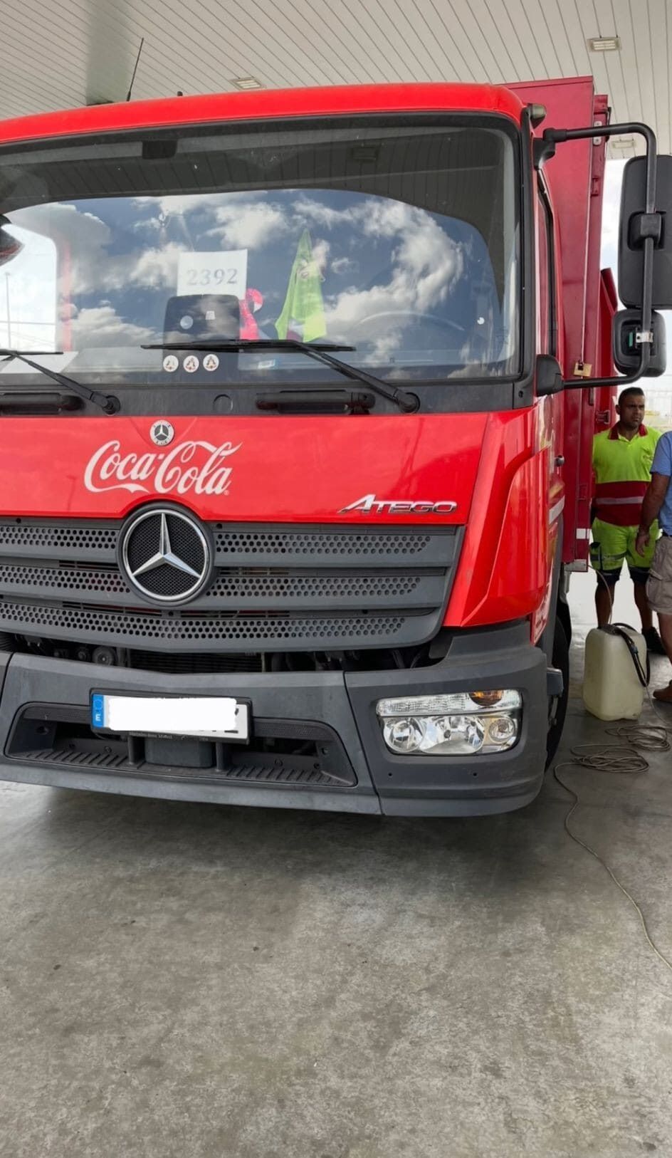 Un camión rojo de Coca Cola está estacionado en una gasolinera.