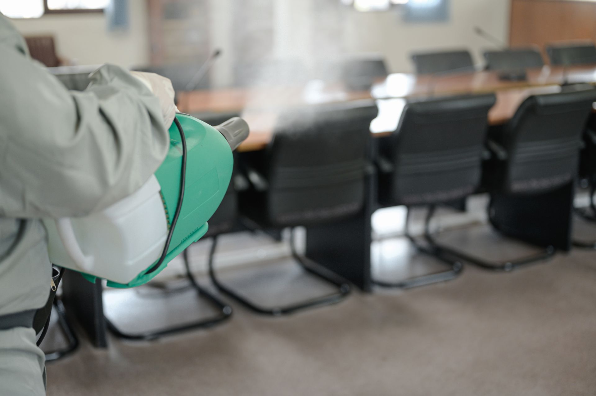 Un agent pulvérise un produit dans une salle de réunion.