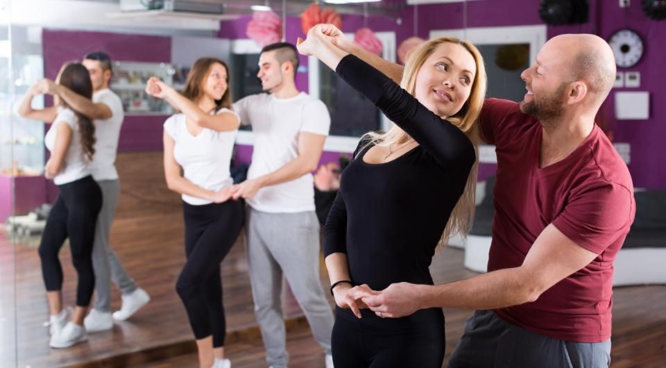 Eine Gruppe junger Leute tanzt zusammen in einem Tanzstudio. ADTV Tanzschule Baulig UG