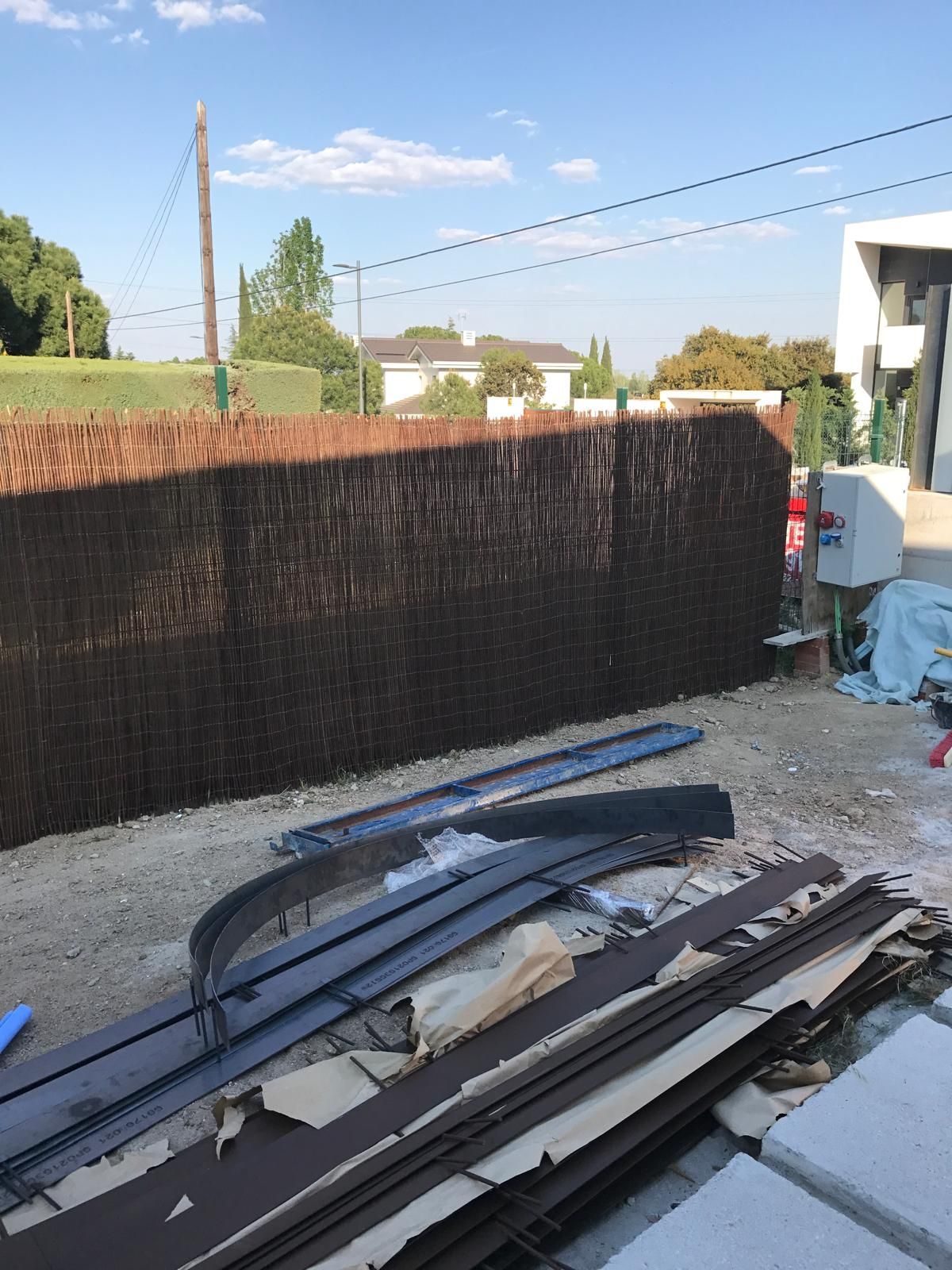 Valla tejida marrón en construcción con herramientas y materiales en el suelo.