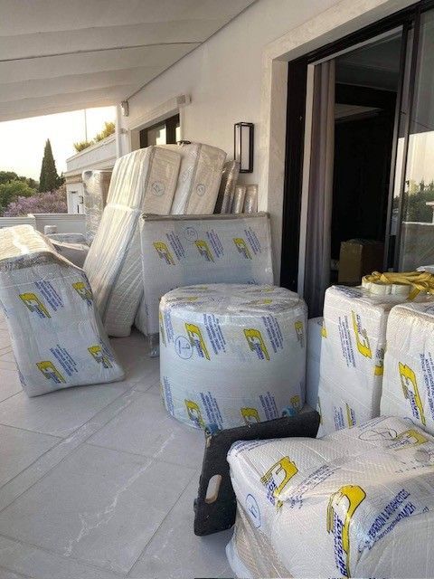 Τυλιγμένα έπιπλα στοιβαγμένα σε ένα μπαλκόνι δίπλα σε μια ανοιχτή συρόμενη πόρτα
