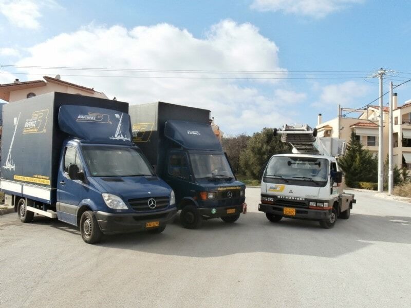 Τρία φορτηγά παράδοσης παρκαρισμένα σε έναν ηλιόλουστο δρόμο κοντά σε σπίτια