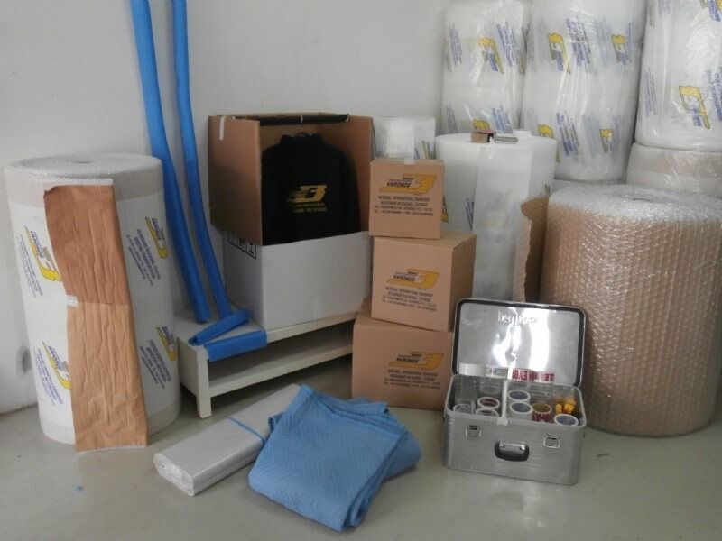 Στοιβαγμένα κουτιά μετακόμισης, τυλιγμένα αντικείμενα και προμήθειες συσκευασίας σε μια αποθήκη.
