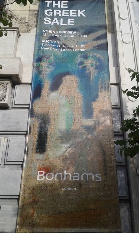 Ψηλή αφίσα του οίκου Bonhams για το «The Greek Sale» με μπλε και καφέ αφηρημένα έργα τέχνης σε τοίχο κτιρίου