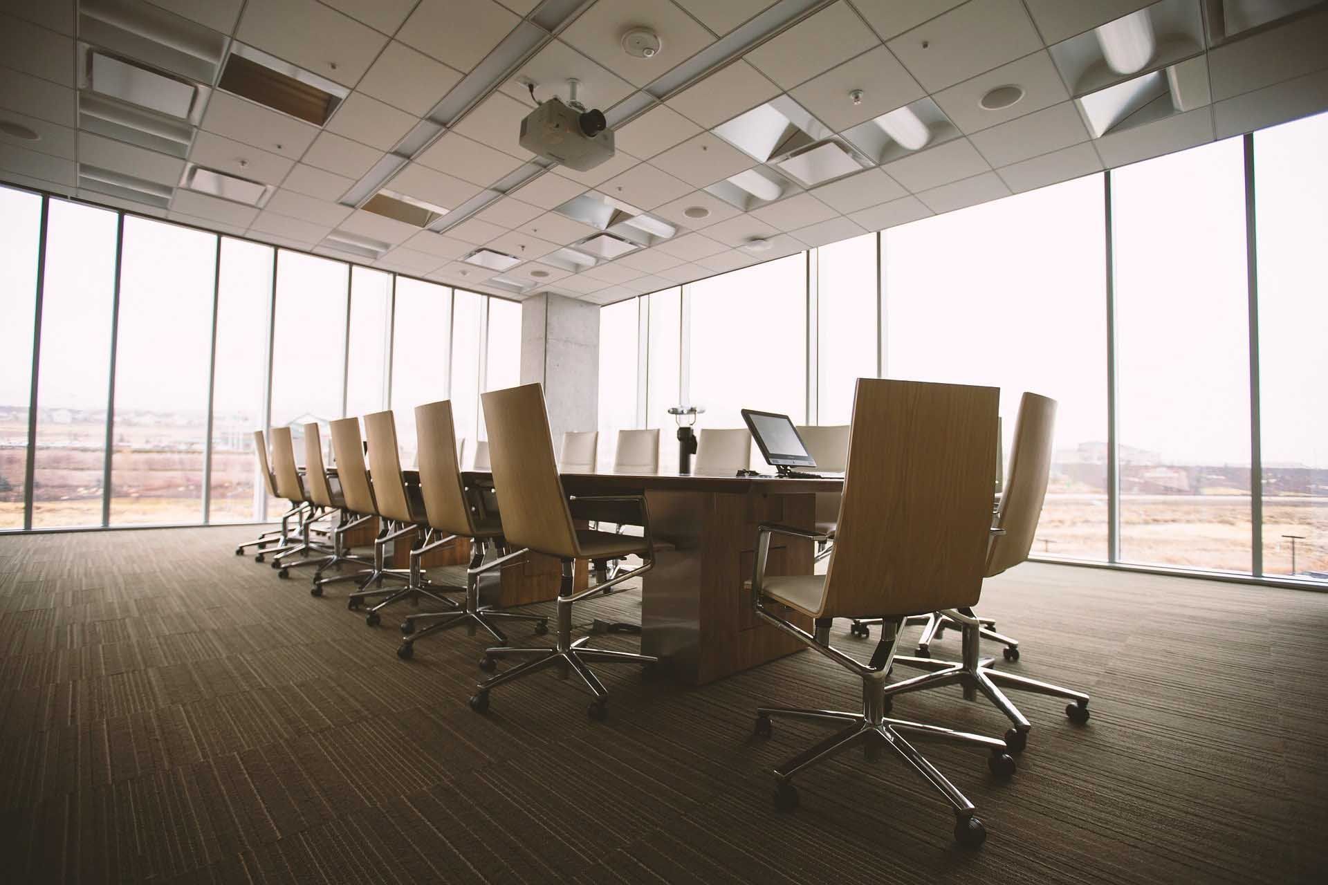 Una sala de conferencias con una mesa larga y sillas y muchas ventanas.