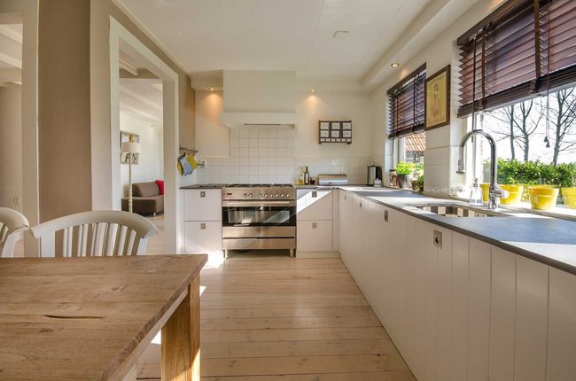 Una cocina con gabinetes blancos y una mesa y sillas de madera.