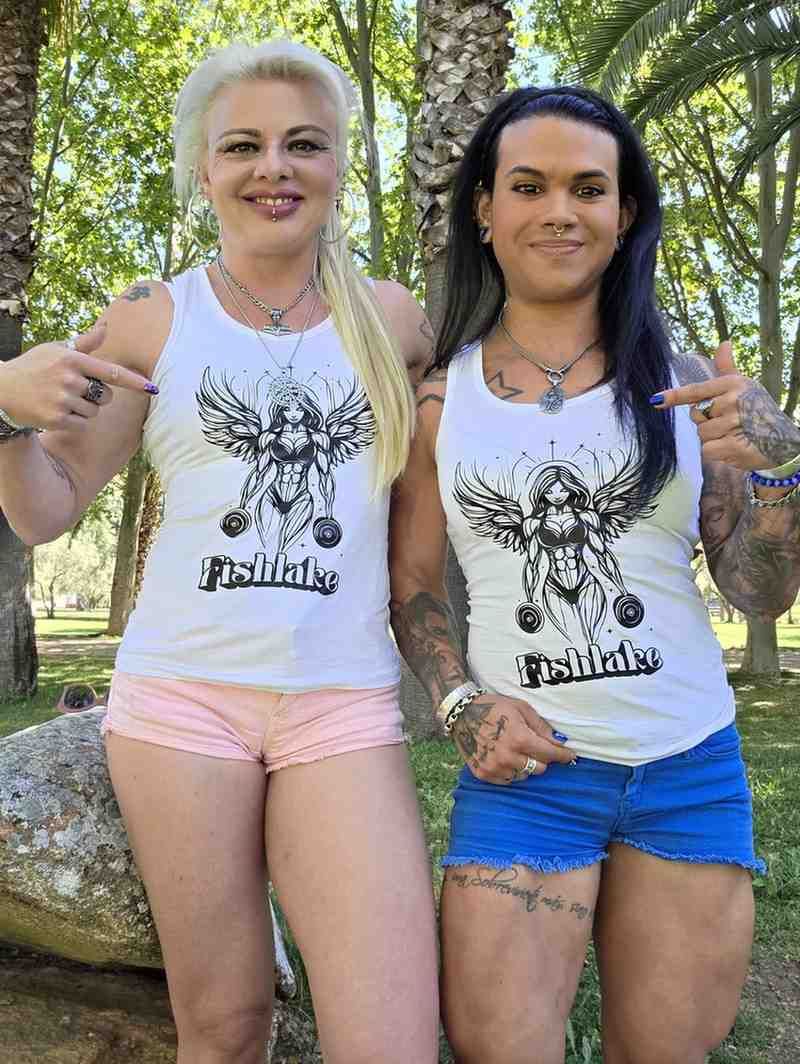 Dos personas de pie al aire libre, sonriendo, vistiendo camisetas blancas sin mangas a juego con diseños de árboles.