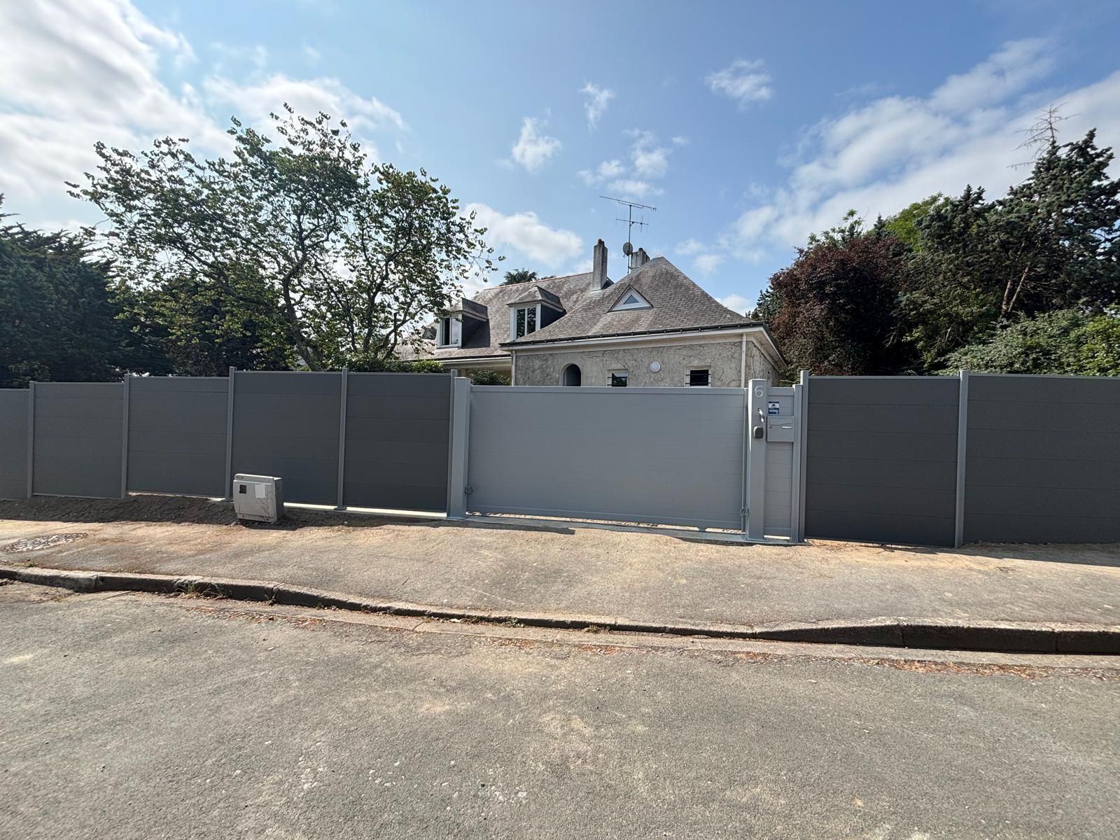 Prise de vue d'une clôture occultante et d'une portail d'une grande maison individuelle vue de l'extérieure