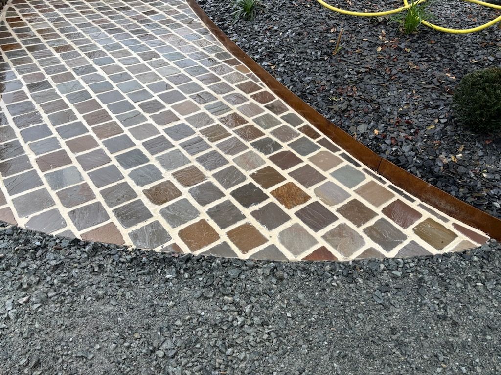 Allée piétonne créée en pavés grès des indes au cœur d'un massif paysager