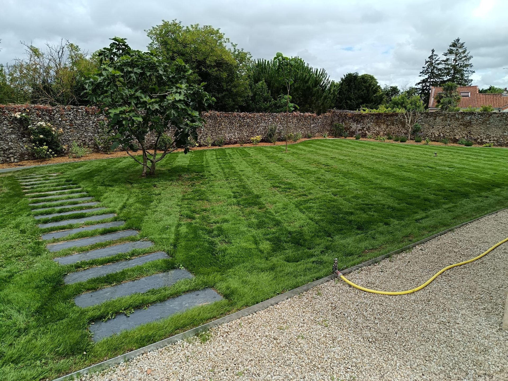 Entretien et tonte d'un jardin avec chemin en pierre