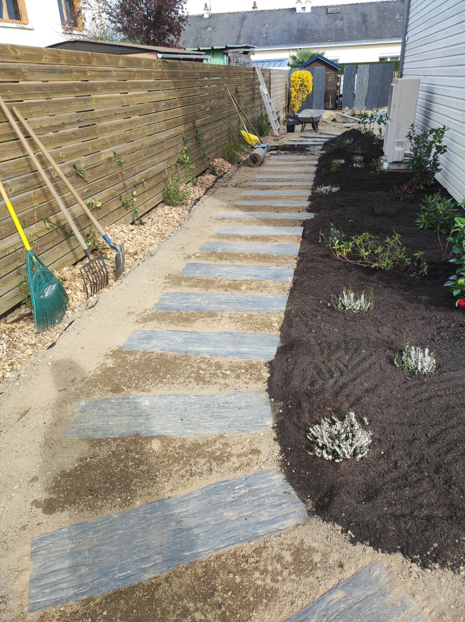 Création d'un chemin en dalles de pierre sur le côté du maison pour accéder au jardin