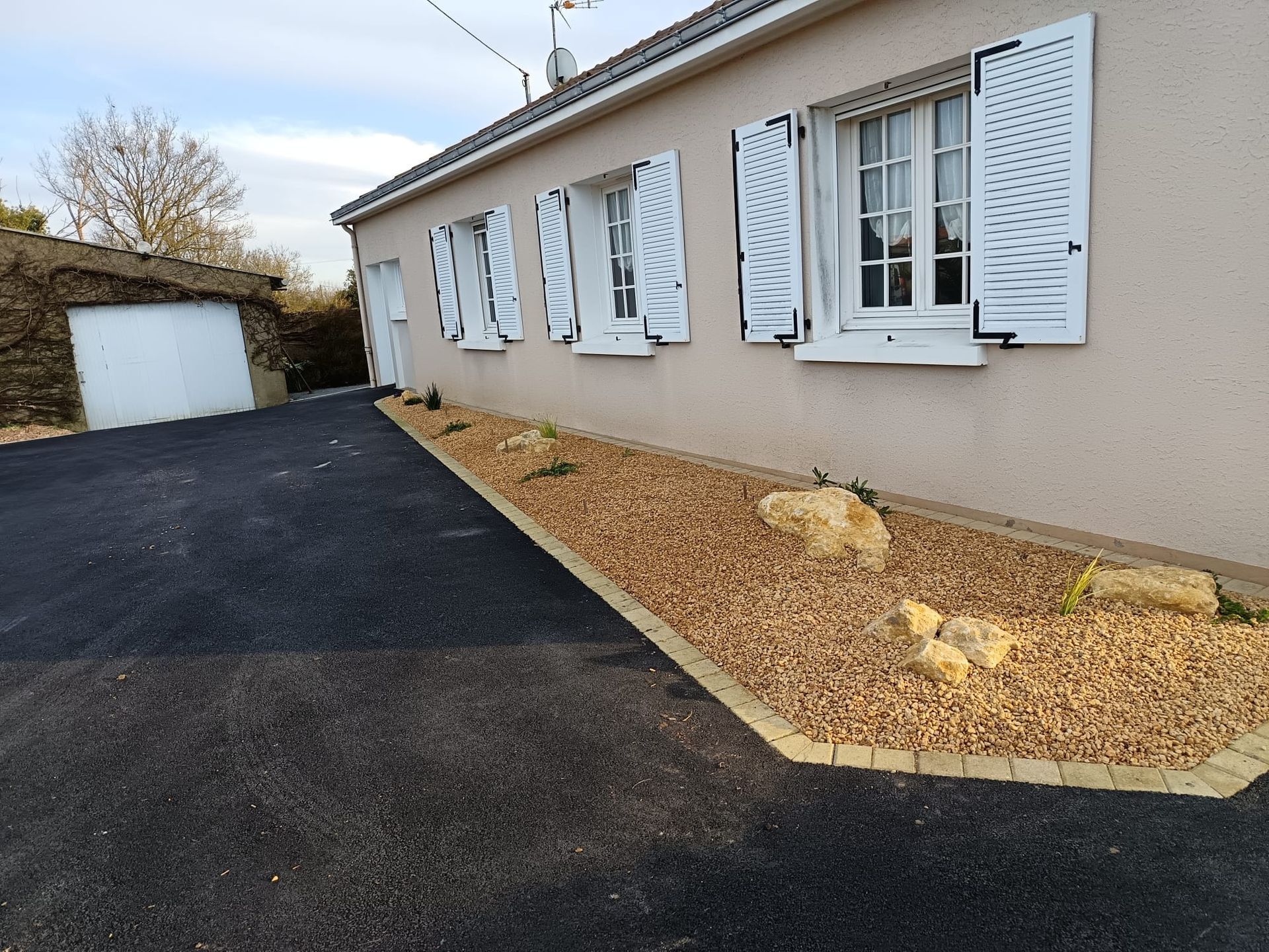 Plantations, pierres et graviers installés en décoration devant une maison individuelle