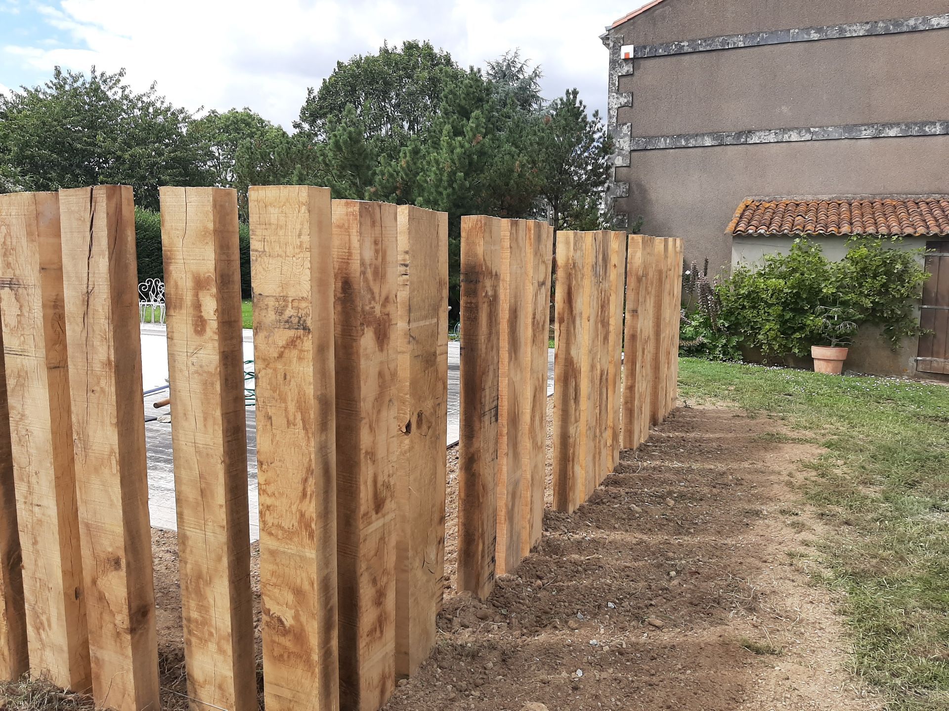 Installation de traverses en bois autour d'un aménagement paysager