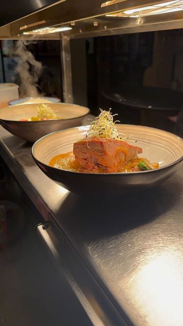 Deux plats présentés dans une assiette défilent sous une lumière chaude, laissant apparaître la garniture et la sauce.