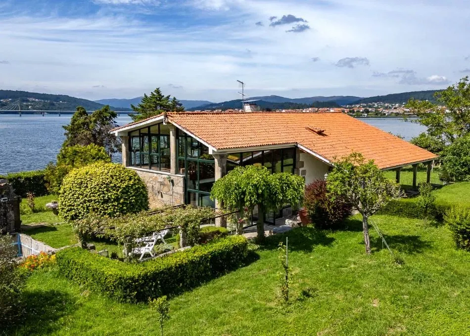 Casa blanca con piscina y cielo azul. Escaleras que conducen al balcón. Parrilla en el patio.