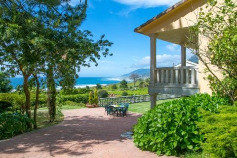 Comedor con mesa, sillas, sofá y grandes ventanales con vistas.
