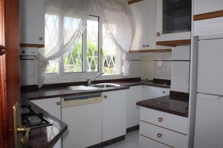 Casa de piedra con techo de tejas rojas y extensión de estuco amarillo. Pequeño patio con césped y muebles de exterior.