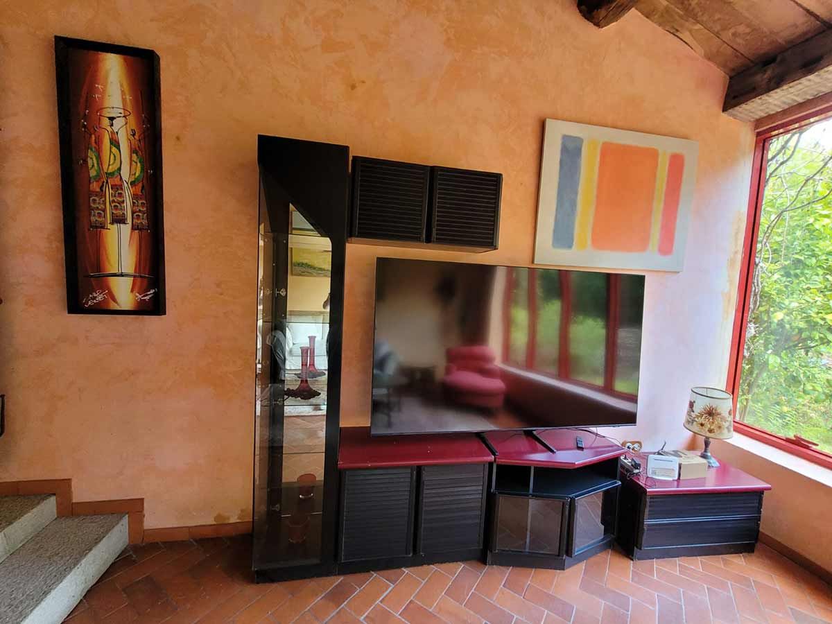 Sala de estar con moderno centro de entretenimiento, TV, obras de arte y ventana con vista a la vegetación.