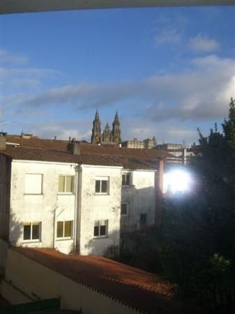 Casa de piedra con techo de tejas rojas y extensión de estuco amarillo. Pequeño patio con césped y muebles de exterior.