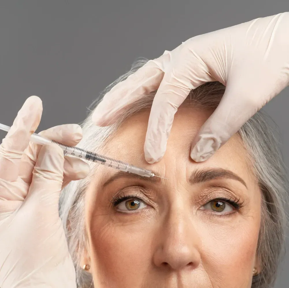 Una mujer recibe una inyección de botox en la frente.