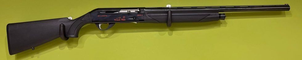 Una escopeta negra con culata y guardamanos oscuros, sobre un fondo verde amarillento.