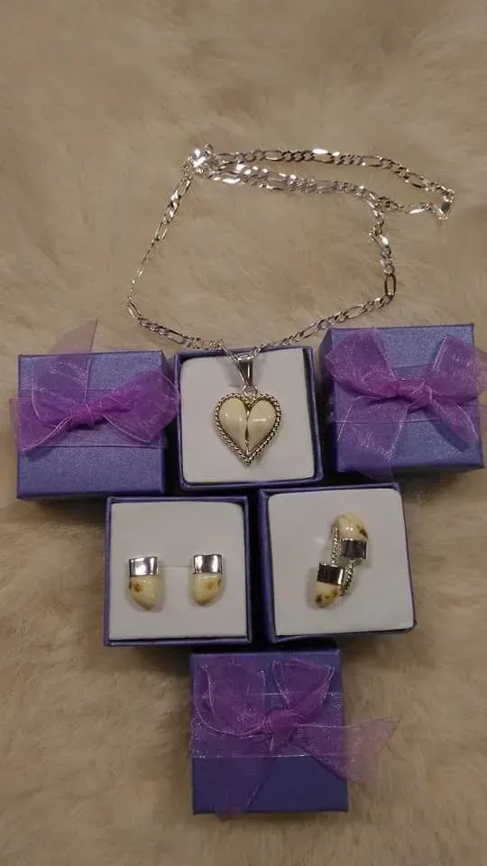Conjunto de joyas: collar de plata, colgante de corazón, pendientes y gemelos en cajas moradas con cinta.