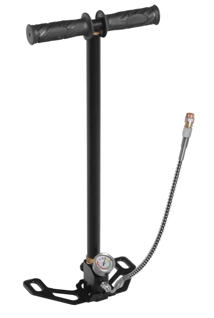 Bomba manual negra con manija, base de pie y manómetro, conectada a una manguera con un accesorio.